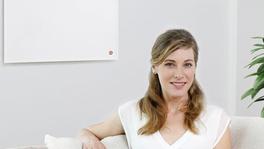 Frau auf Couch vor easyTherm® Infrarotheizung comfort