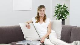 Femme dans le couch avec chauffage infrarouge au mur